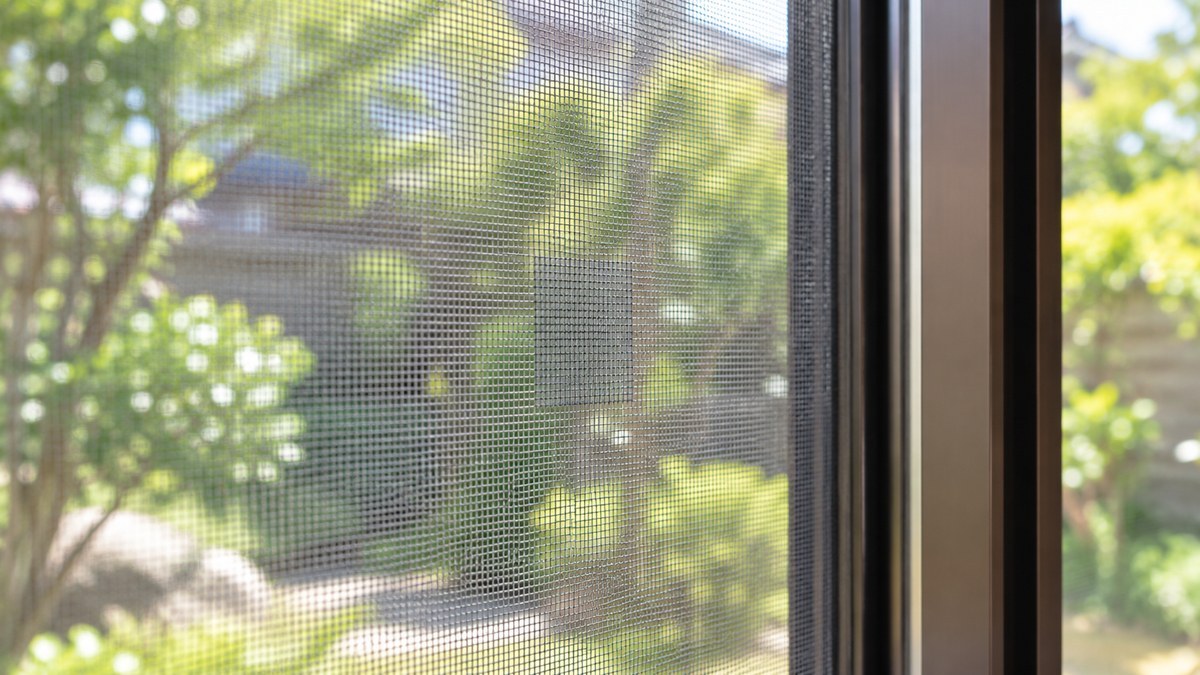 補修後の網戸。破れの上に貼ったグレーのパッチが周囲になじんでいる状態