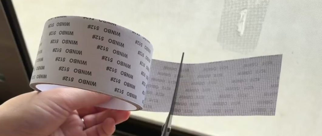 網戸補修テープを破れの大きさに合わせてハサミで切っているところ