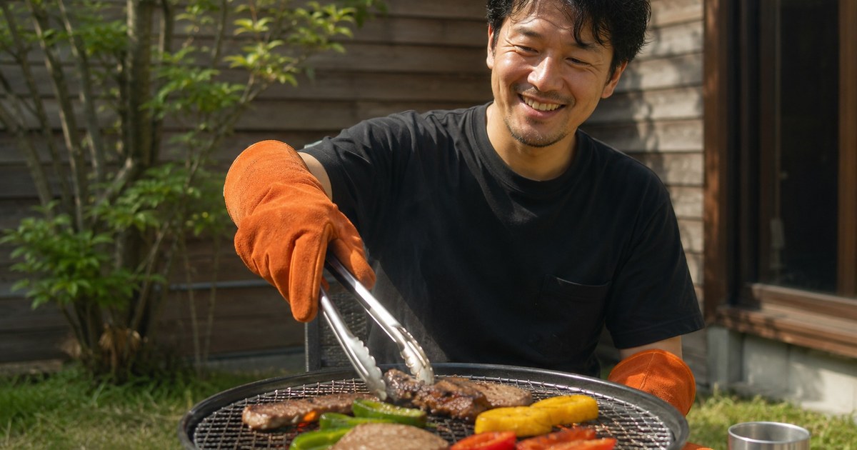 BBQで牛革の耐熱グローブを使って炭火調理をする男性