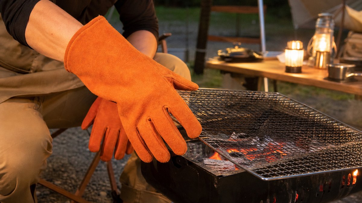 耐熱グローブをつけた手で炭火の焼き網を調整する様子