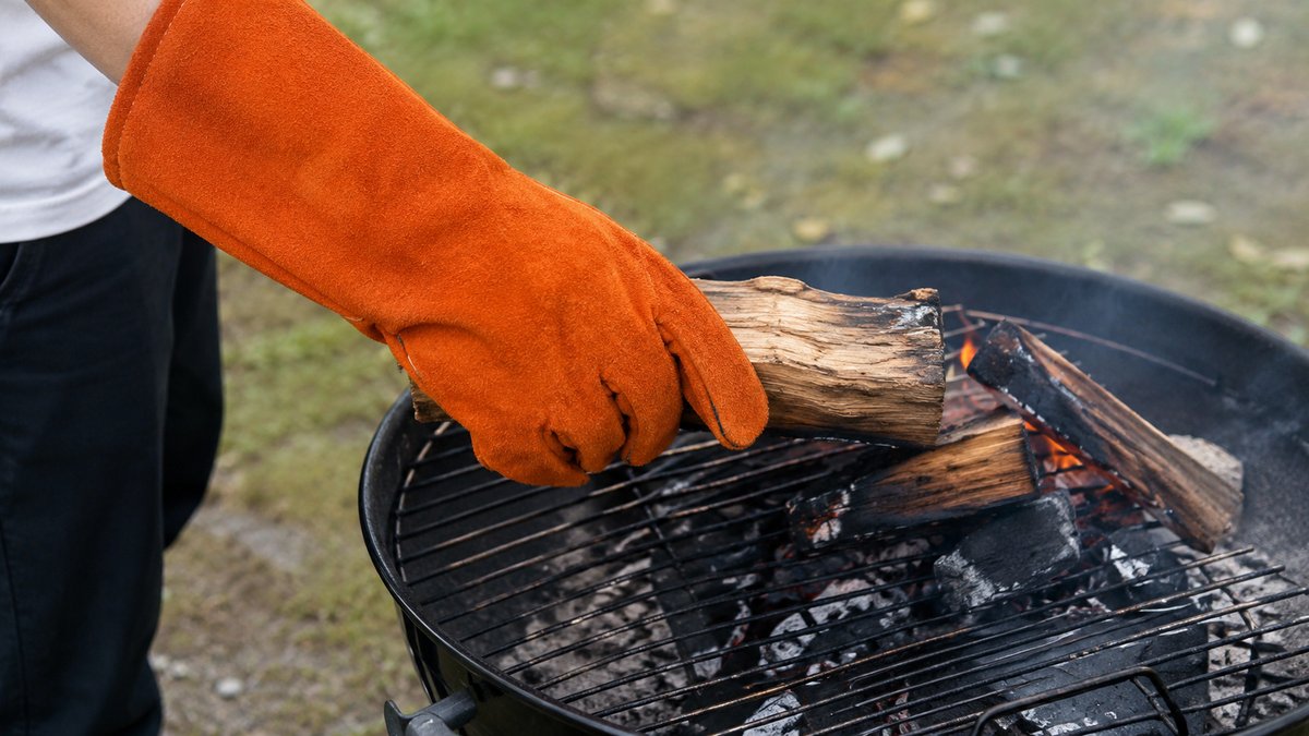 牛革素材の耐熱グローブでBBQの薪をつかむシーン